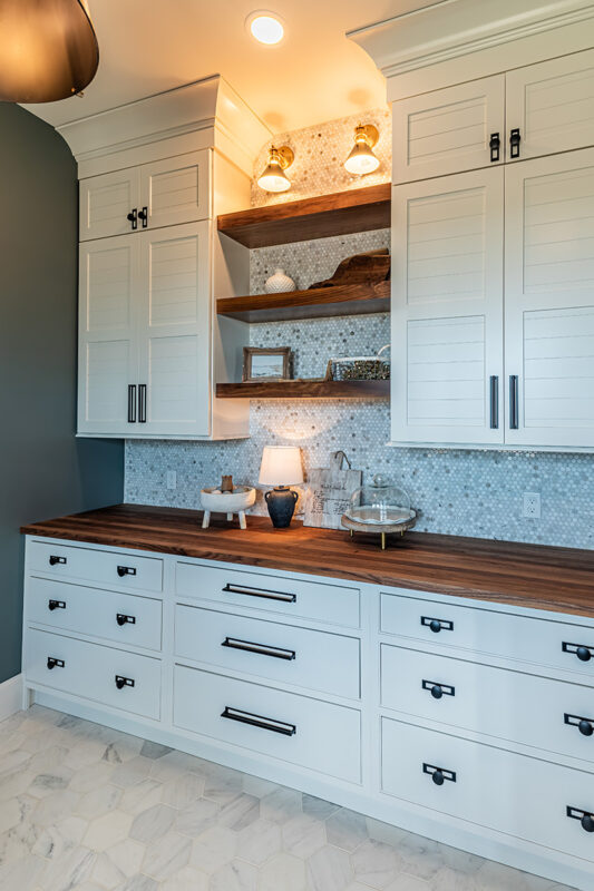 white cabinetry storing with wood countertops and multicolored hexagonal tile backsplash.