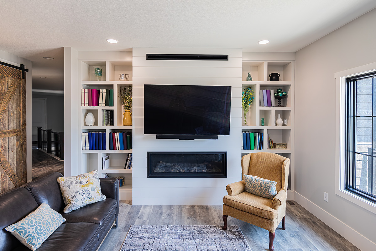 White built in cabinets around a built in fireplace along the narrow wall of a living room.