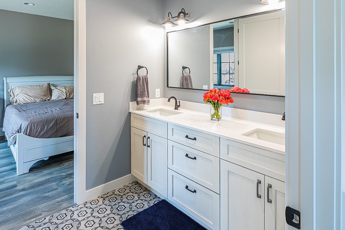 bathroom with white vanity and large rectangular mirror that opens to bedroom