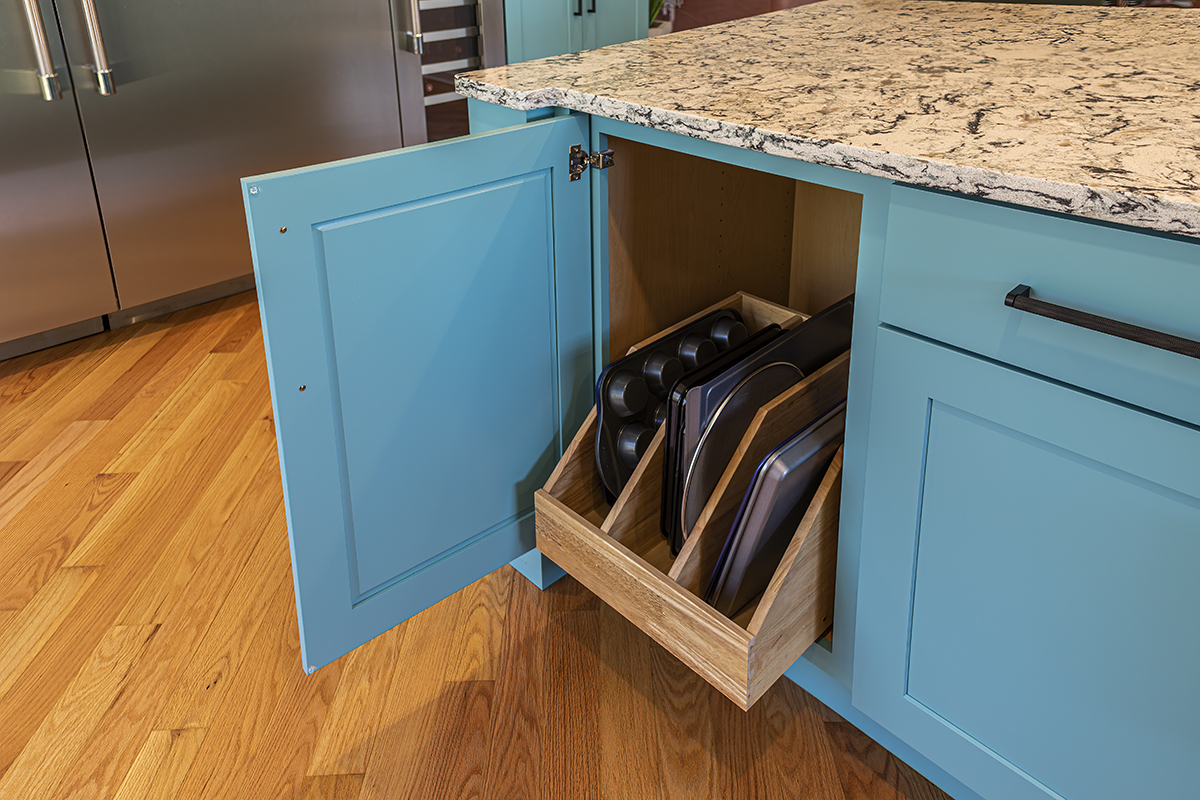 A blue cabinet in a kitchen that features a cabinet organizer for pans and trays