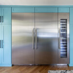 large teal blue pantry-style cabinets around a commercial style fridge that also has a wine chiller attached.