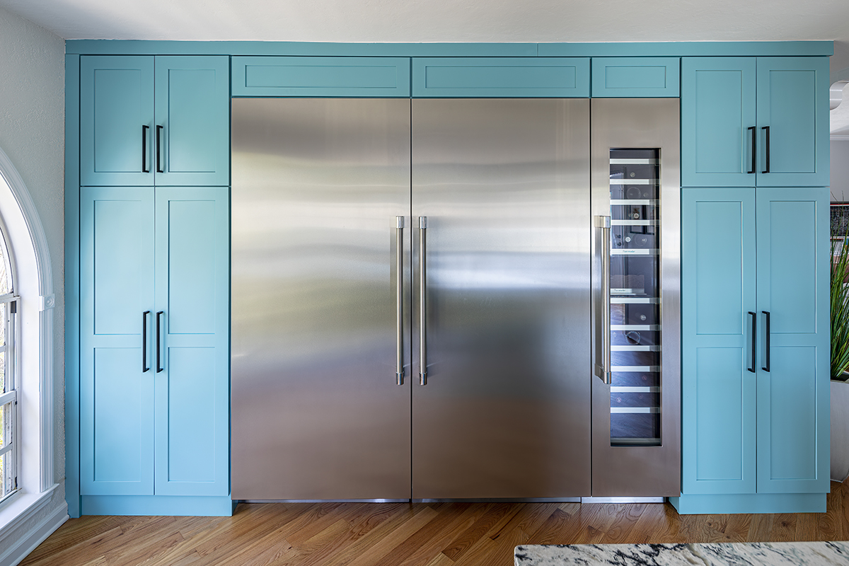 large teal blue pantry-style cabinets around a commercial style fridge that also has a wine chiller attached.