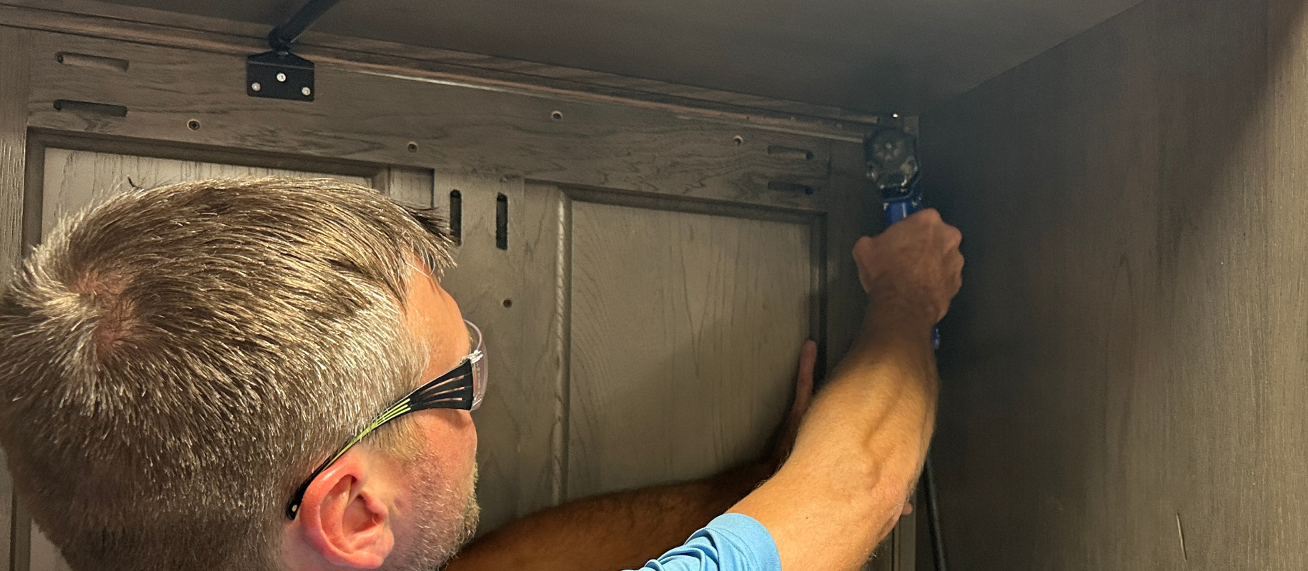 man building cabinets using drill, wearing safety glasses