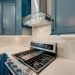 Blue painted kitchen cabinets and stove with hood