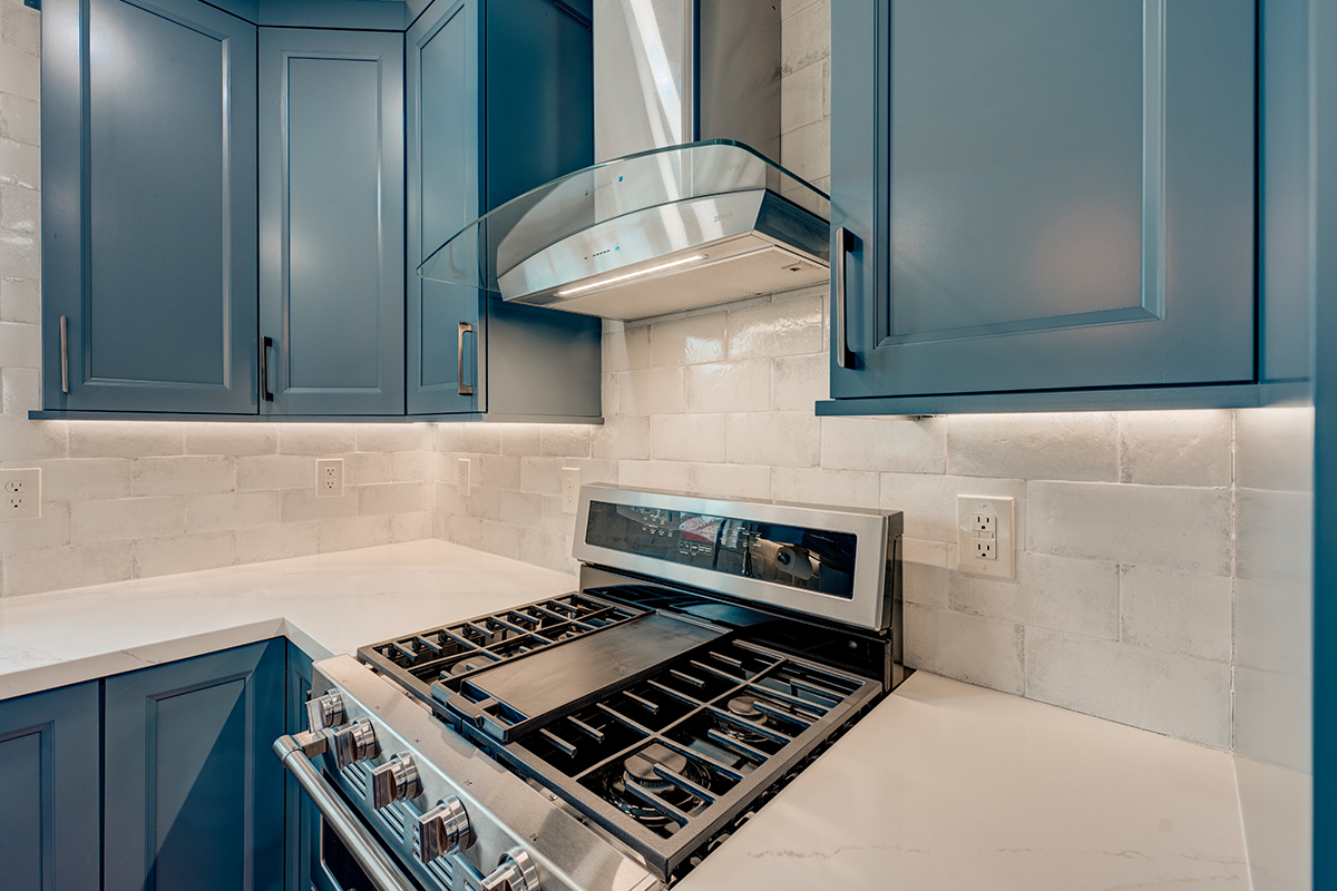 Blue painted kitchen cabinets and stove with hood