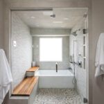 Bathroom shower behind glass with bench seating and tub