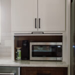 White kitchen appliance storage cabinet with microwave inside.