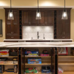 Stained home bar with island seating. Island storage doors are open to show shelves filled with games, etc.