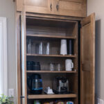 Beverage center cabinet with pocket doors hiding appliances, cups and mugs.