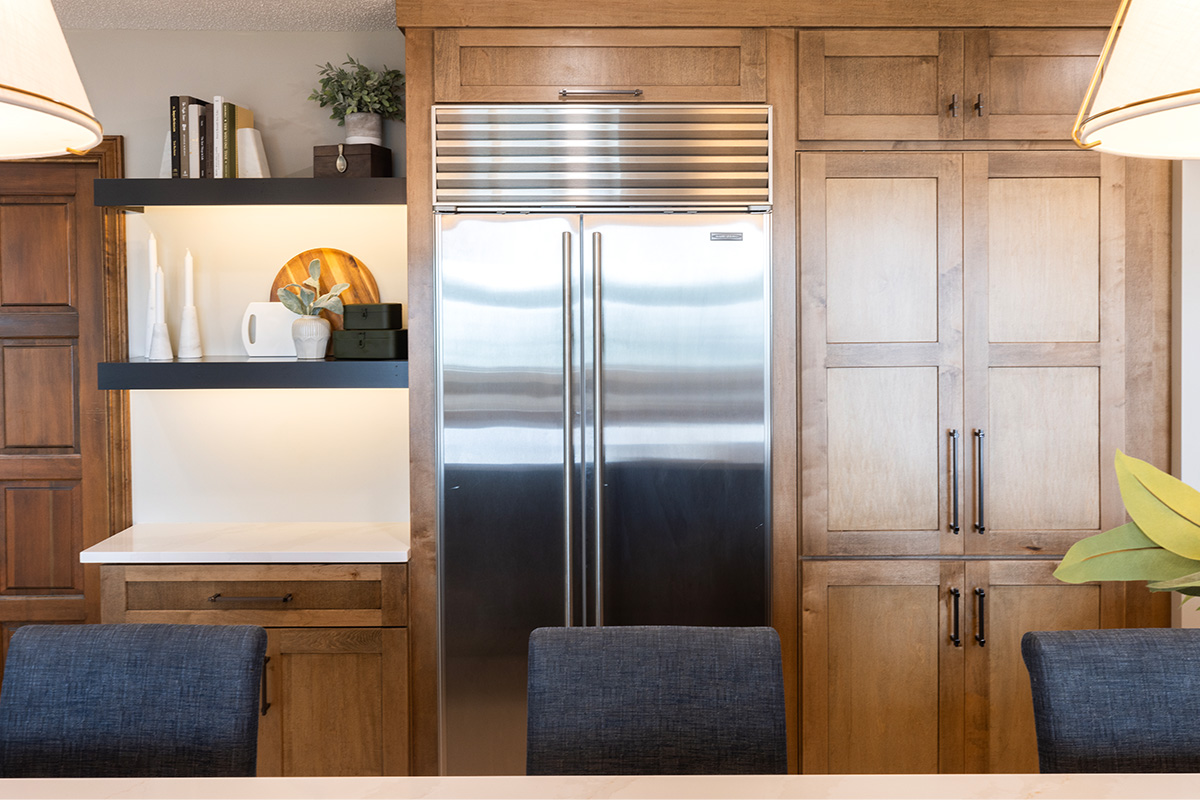 Large side by side fridge enclosed by stained end panels with a walk in pantry door to the right.