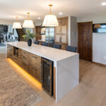 Long kitchen island with tv and fridge beyond