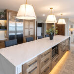 Long kitchen island with tv and fridge beyond