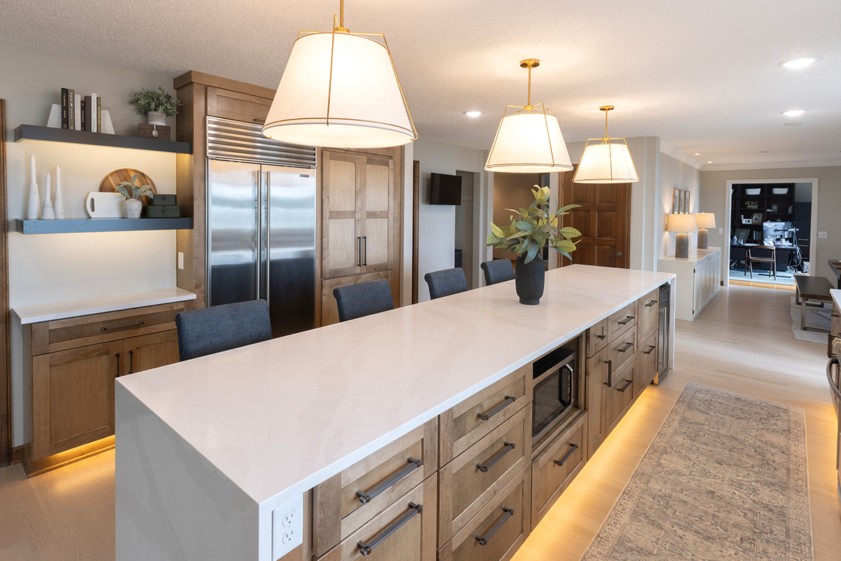 Long kitchen island with tv and fridge beyond