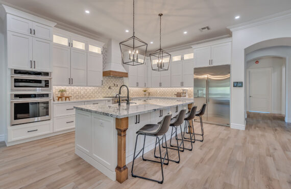 White kitchen with stained accent posts on island and apron on hood.