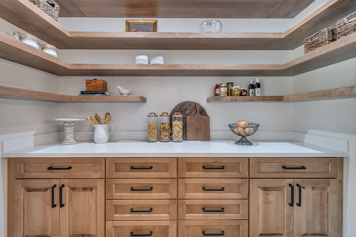 Pantry with stained cabinets and floating shelves.