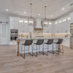 White kitchen with stained accent posts on island and apron on hood.