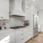 White painted kitchen cabinets with chimney range hood above cooktop