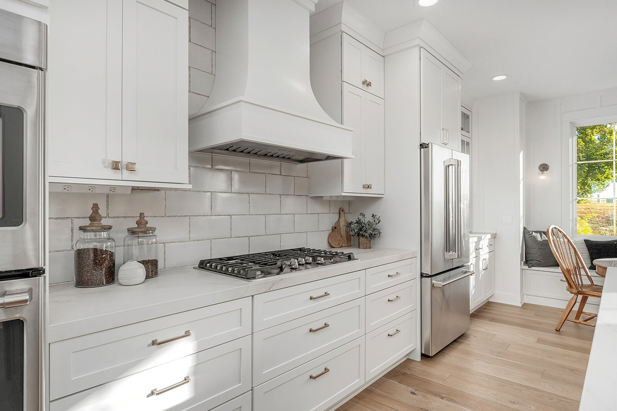 White painted kitchen cabinets with chimney range hood above cooktop