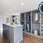 Painted walk-in closet cabinets with hanging closes and a center island for additional storage