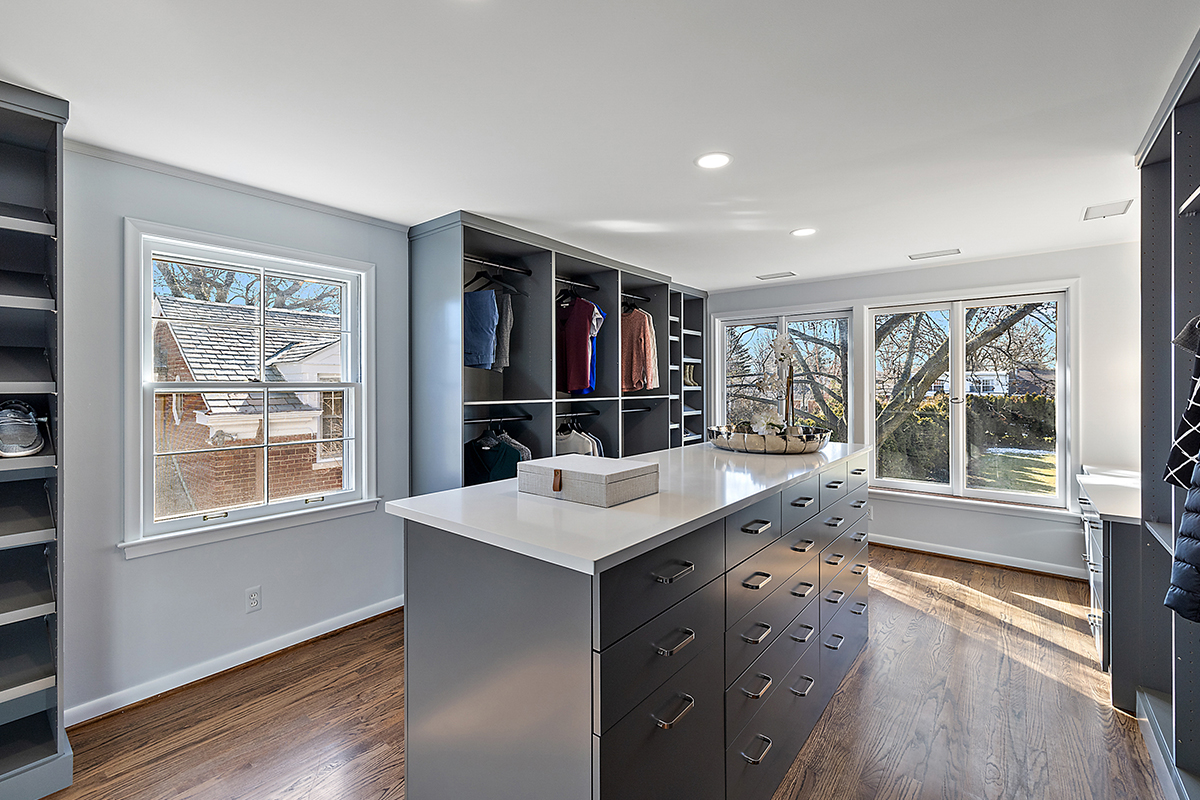 Painted walk-in closet cabinets with hanging closes and a center island for additional storage