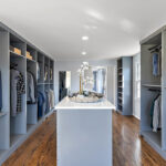 Painted walk-in closet cabinets with hanging closes and a center island for additional storage