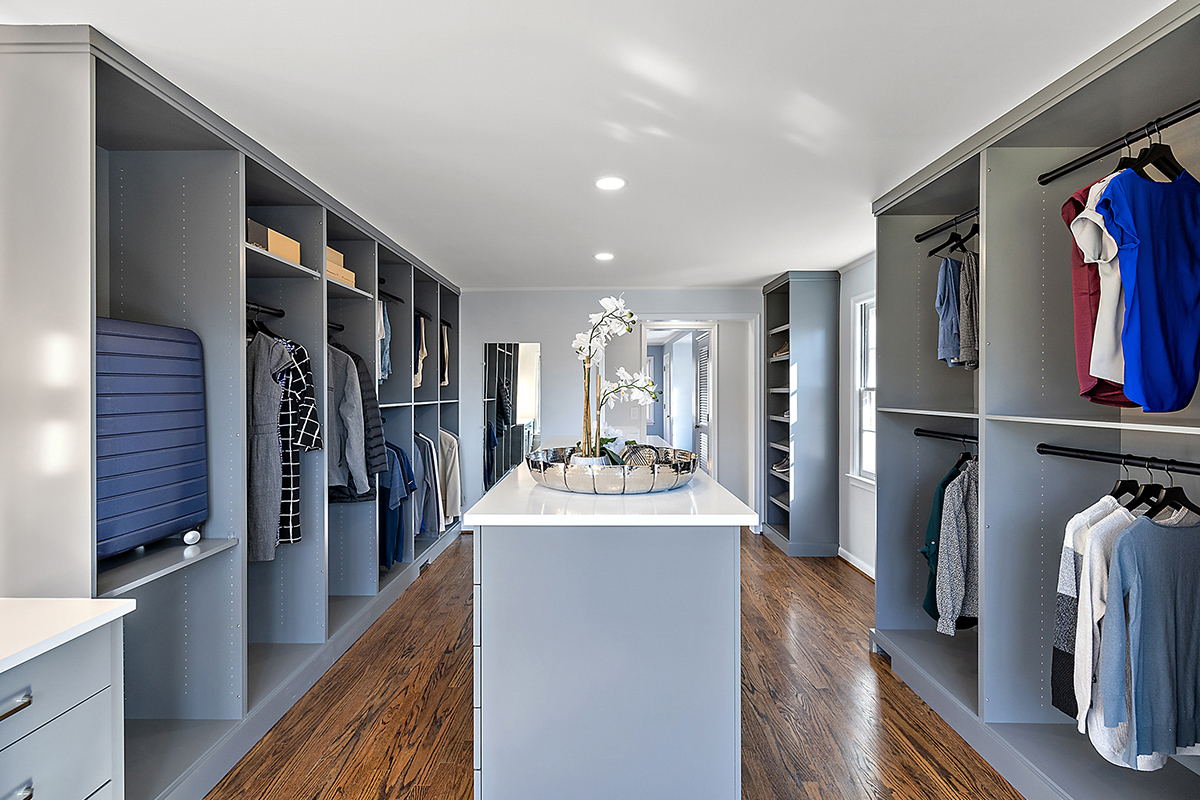 Painted walk-in closet cabinets with hanging closes and a center island for additional storage