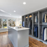 Painted walk-in closet cabinets with hanging closes and a center island for additional storage