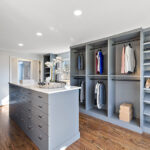 Painted walk-in closet cabinets with hanging closes and a center island for additional storage