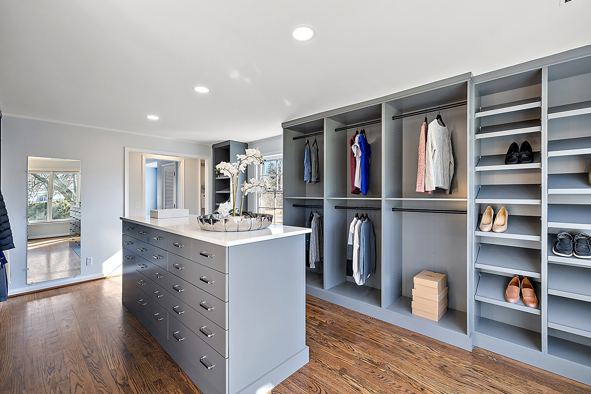 Painted walk-in closet cabinets with hanging closes and a center island for additional storage