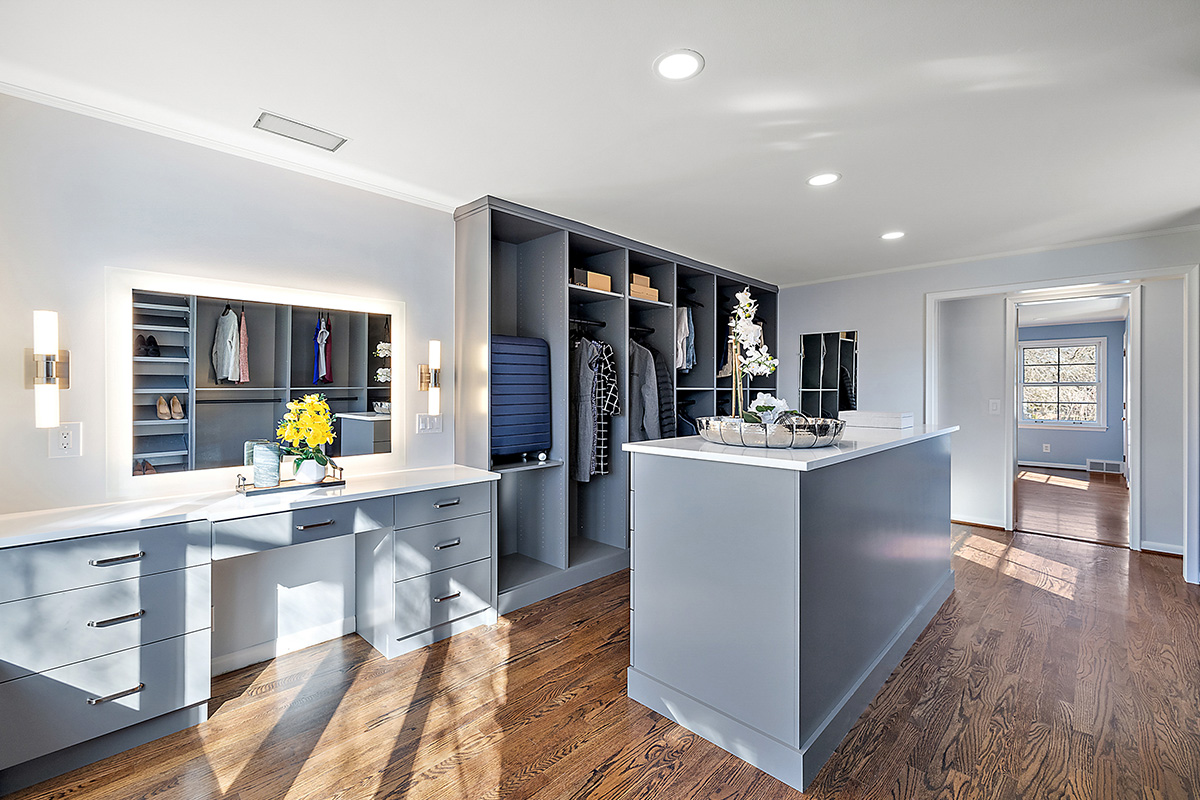 Painted walk-in closet cabinets with hanging closes and a center island for additional storage