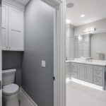 Painted bathroom cabinets with a toilet shown behind a wall