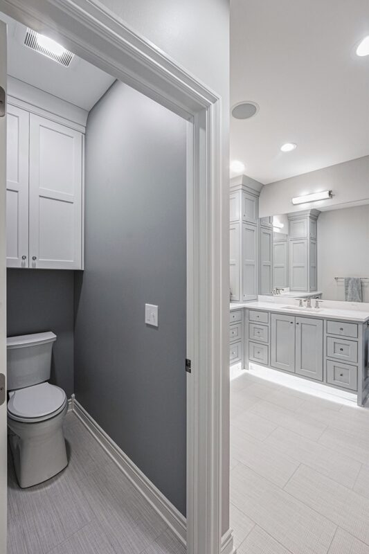 Painted bathroom cabinets with a toilet shown behind a wall