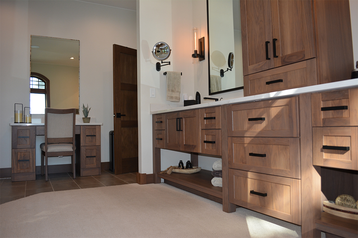 Stained bathroom vanity cabinets with open shelf on the bottom and a countertop wall cabinet splitting 2 sinks