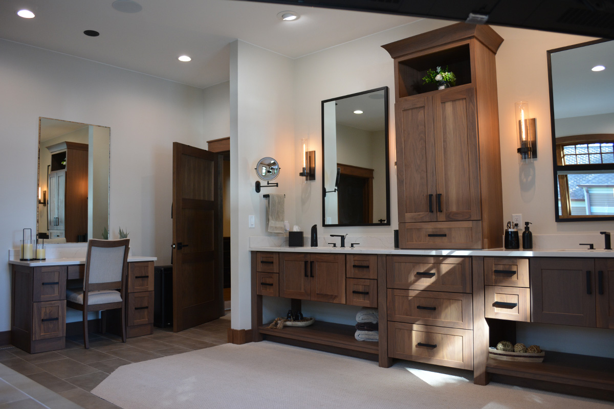 Stained bathroom vanity cabinets with open shelf on the bottom and a countertop wall cabinet splitting 2 sinks