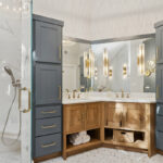 Master bathroom with stained vanity cabinets and painted tall linen cabinets. Also includes a shower with glass walls.