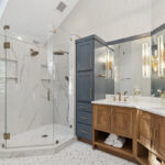 Master bathroom with stained vanity cabinets and painted tall linen cabinets. Also includes a shower with glass walls.