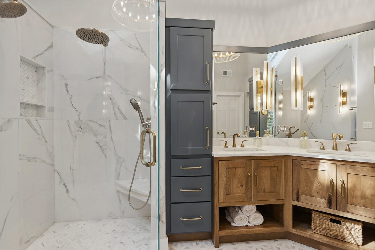 Master bathroom with stained vanity cabinets and painted tall linen cabinets. Also includes a shower with glass walls.