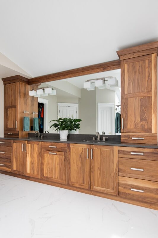 Walnut bathroom cabinets with 2 sinks and countertop storage on each end.