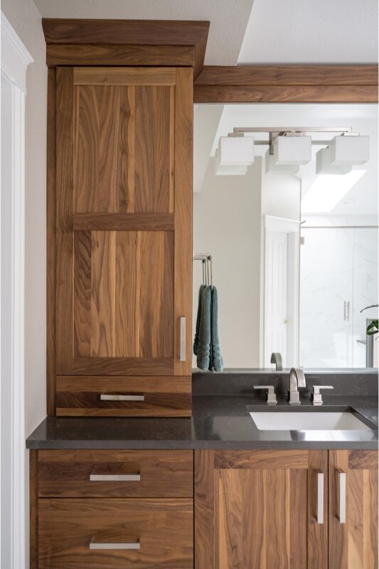 Walnut bathroom cabinets with 2 sinks and countertop storage on each end.