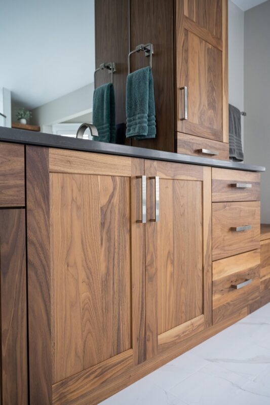 Walnut bathroom cabinets with 2 sinks and countertop storage on each end.