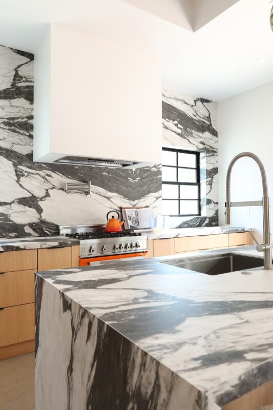 Contemporary kitchen with stained cabinets and marble backsplash