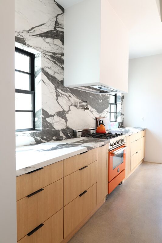 Contemporary kitchen with stained cabinets and marble backsplash