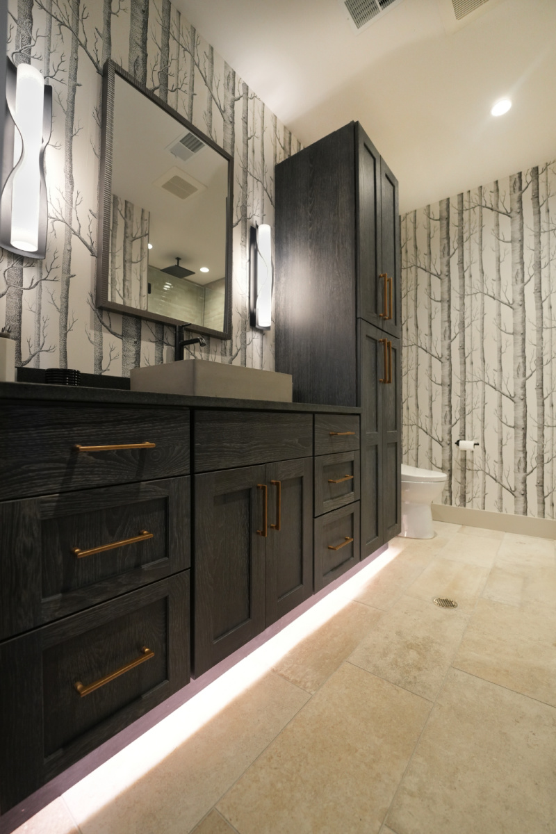 Bathroom vanity cabinets with dark Midnight stain. Bathroom uses "Woods" wall paper.