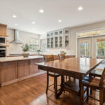 Light brown stained kitchen cabinets and white painted accent cabinets with glass door inserts.