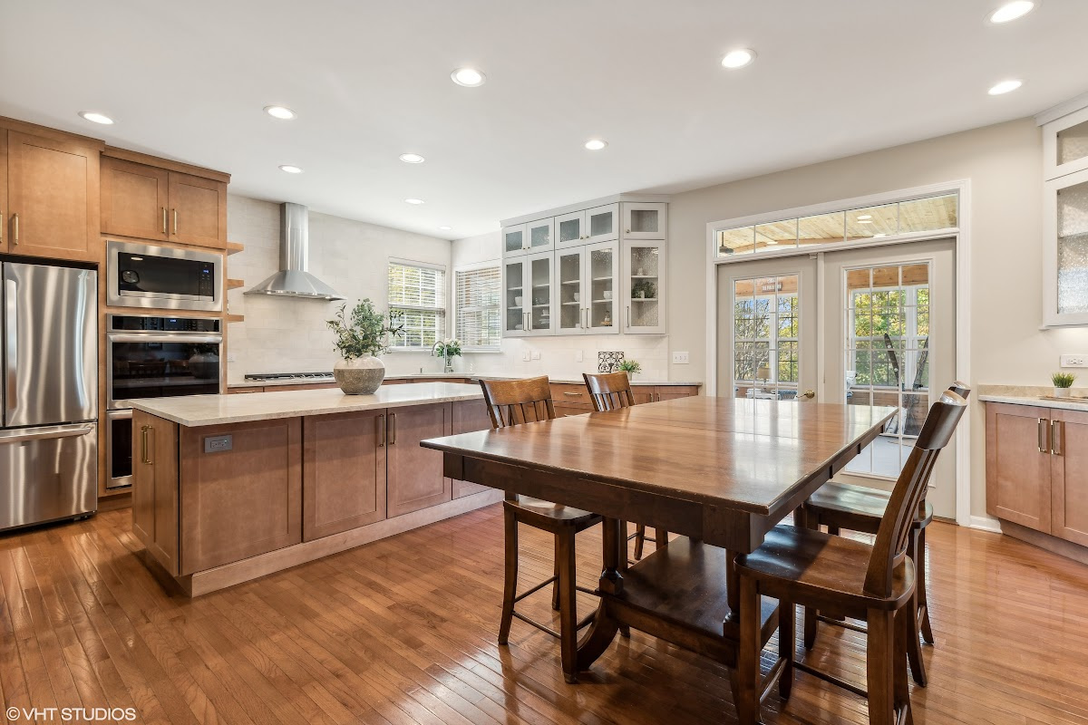 Light brown stained kitchen cabinets and white painted accent cabinets with glass door inserts.