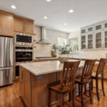 Light brown stained kitchen cabinets and white painted accent cabinets with glass door inserts.