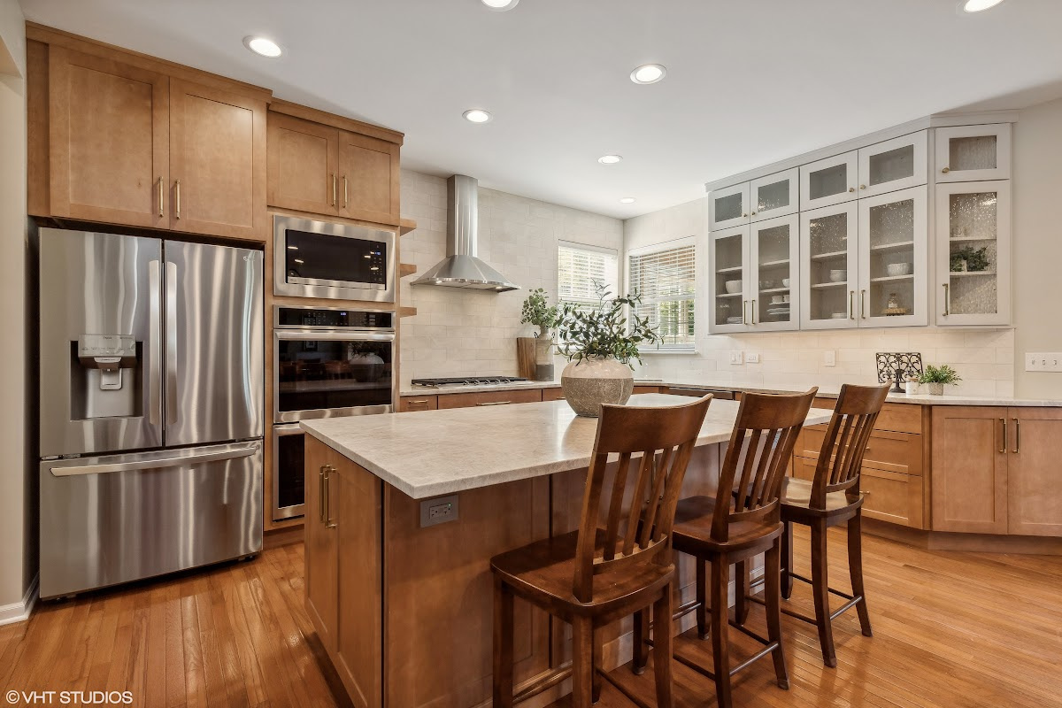 Light brown stained kitchen cabinets and white painted accent cabinets with glass door inserts.
