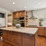Light brown stained kitchen cabinets and white painted accent cabinets with glass door inserts.