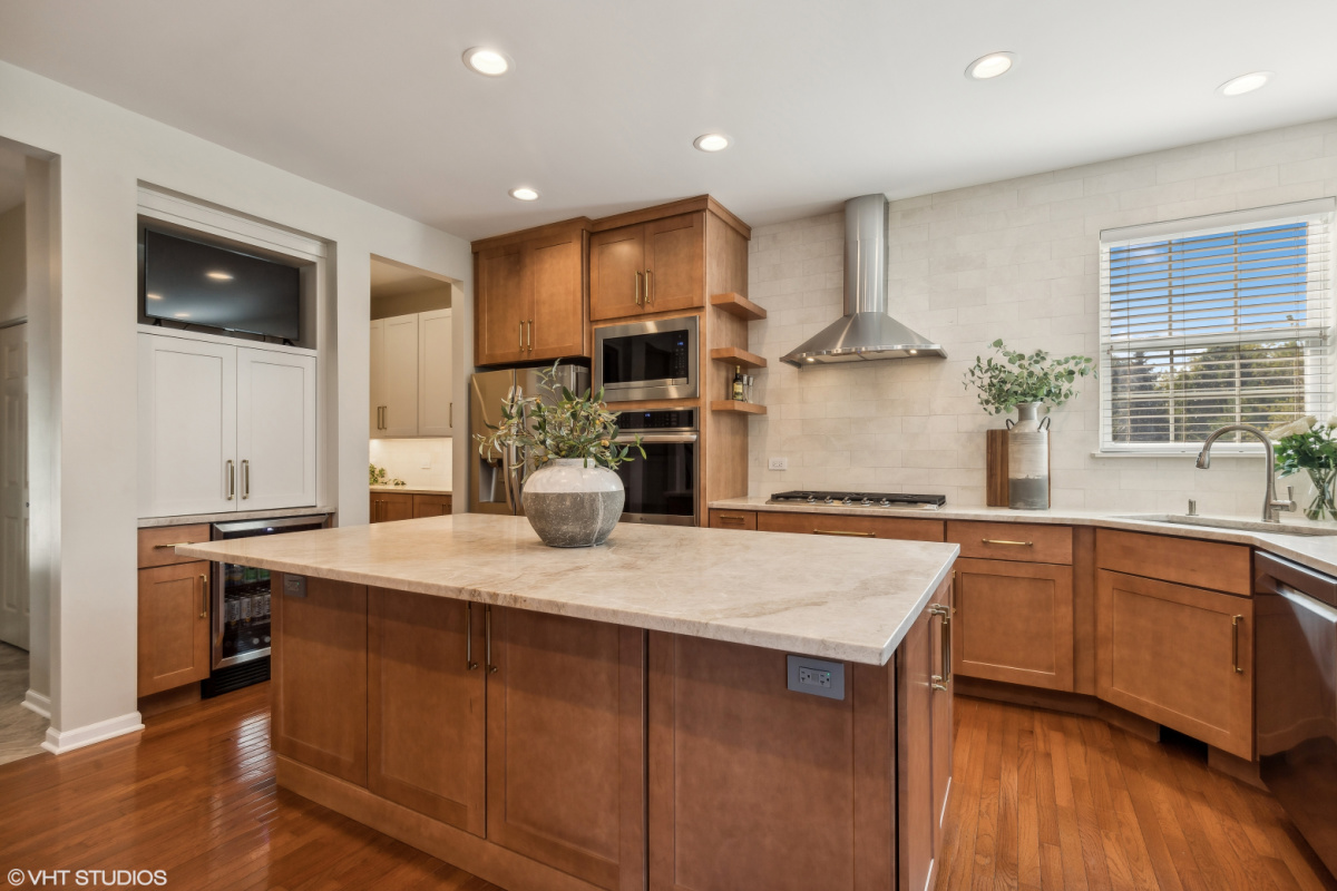 Light brown stained kitchen cabinets and white painted accent cabinets with glass door inserts.