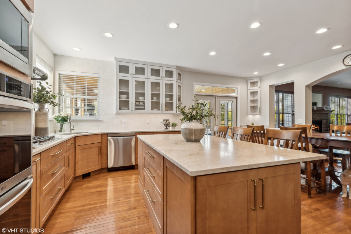 Light brown stained kitchen cabinets and white painted accent cabinets with glass door inserts.